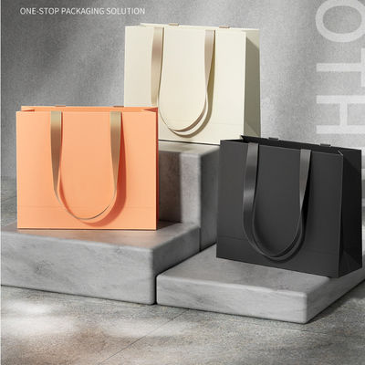 Bolsas de ropa personalizadas Embalaje de lujo de cartón de marfil Kraft papel de bajo precio Bolsa de regalo de compras Logotipo personalizado